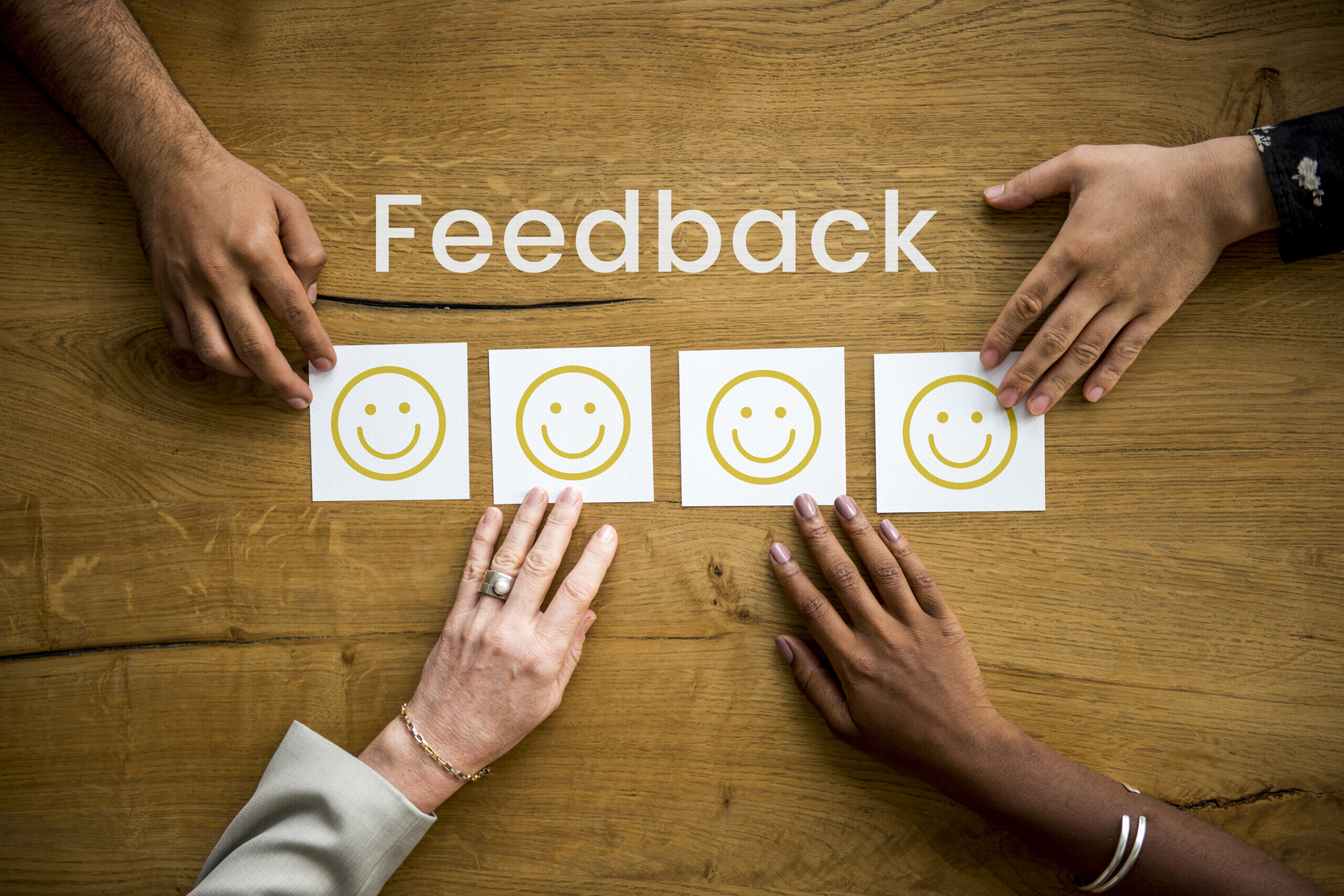 People placing smiley face cards on a table representing real-time feedback and positive evaluations.