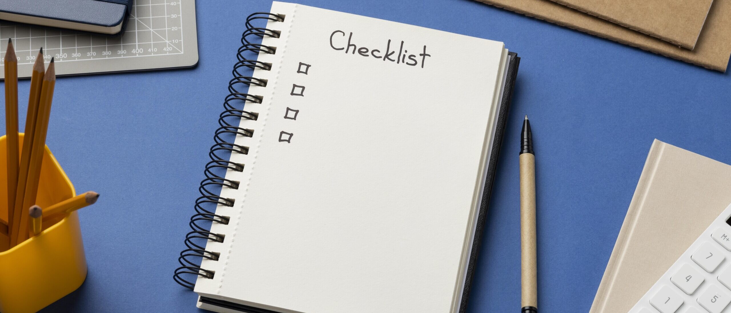 Top view of a notebook showing an HR audit checklist on a desk with pencils and office supplies.