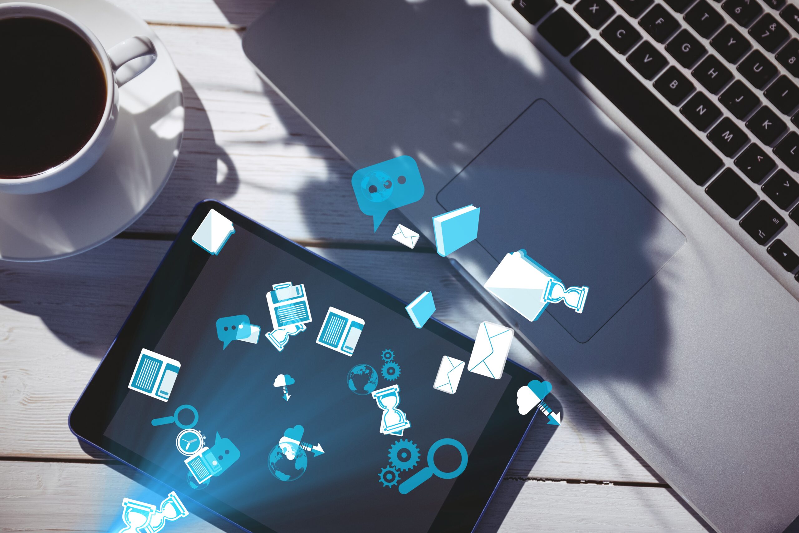 Internal communication software illustrated with digital icons flowing between a laptop and tablet on a desk.