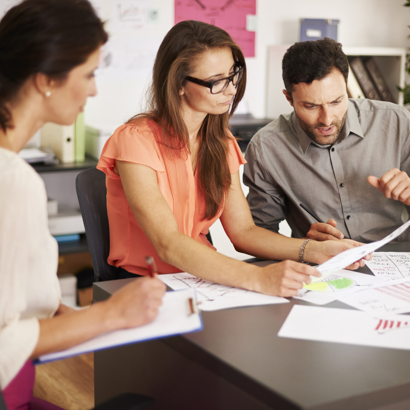 Three professionals reviewing charts and data in an office during a workforce planning meeting