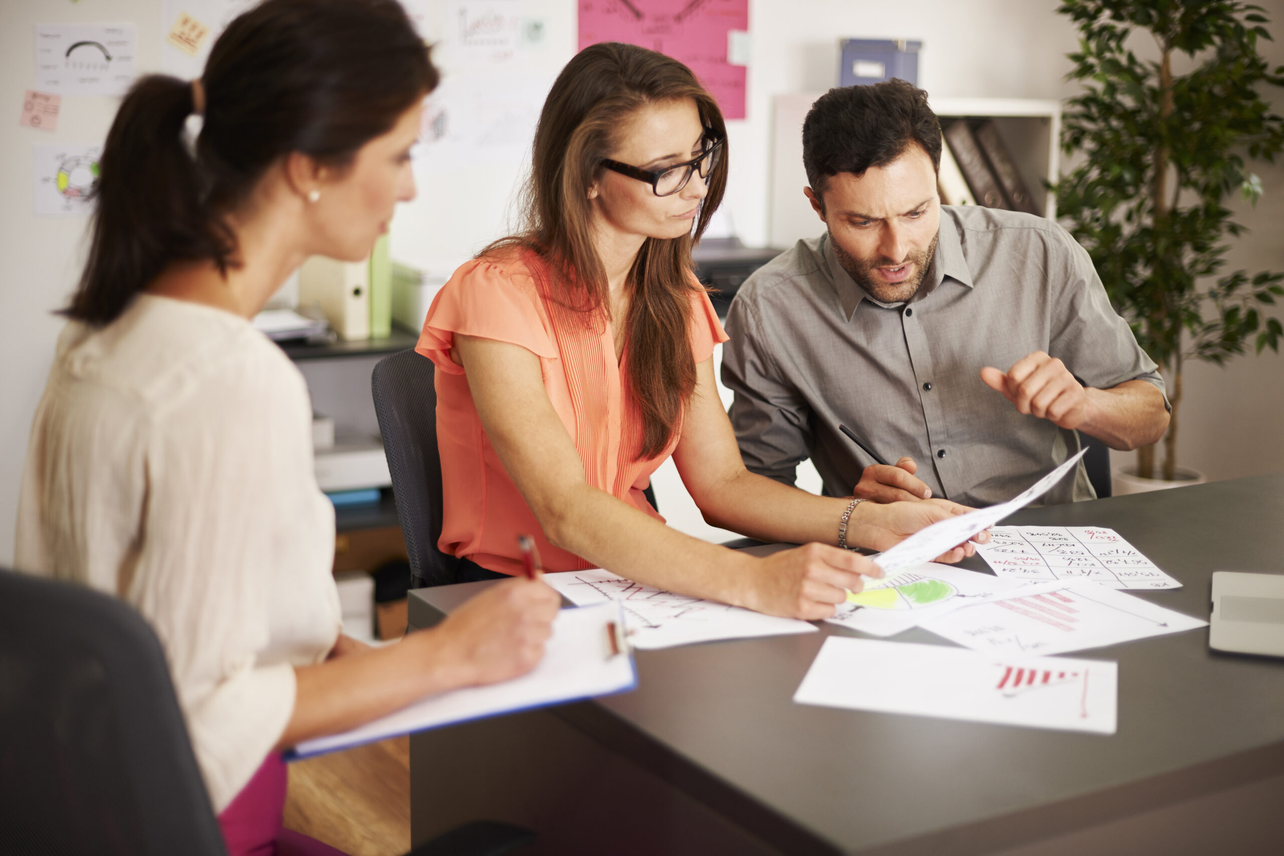 Three professionals reviewing charts and data in an office during a workforce planning meeting