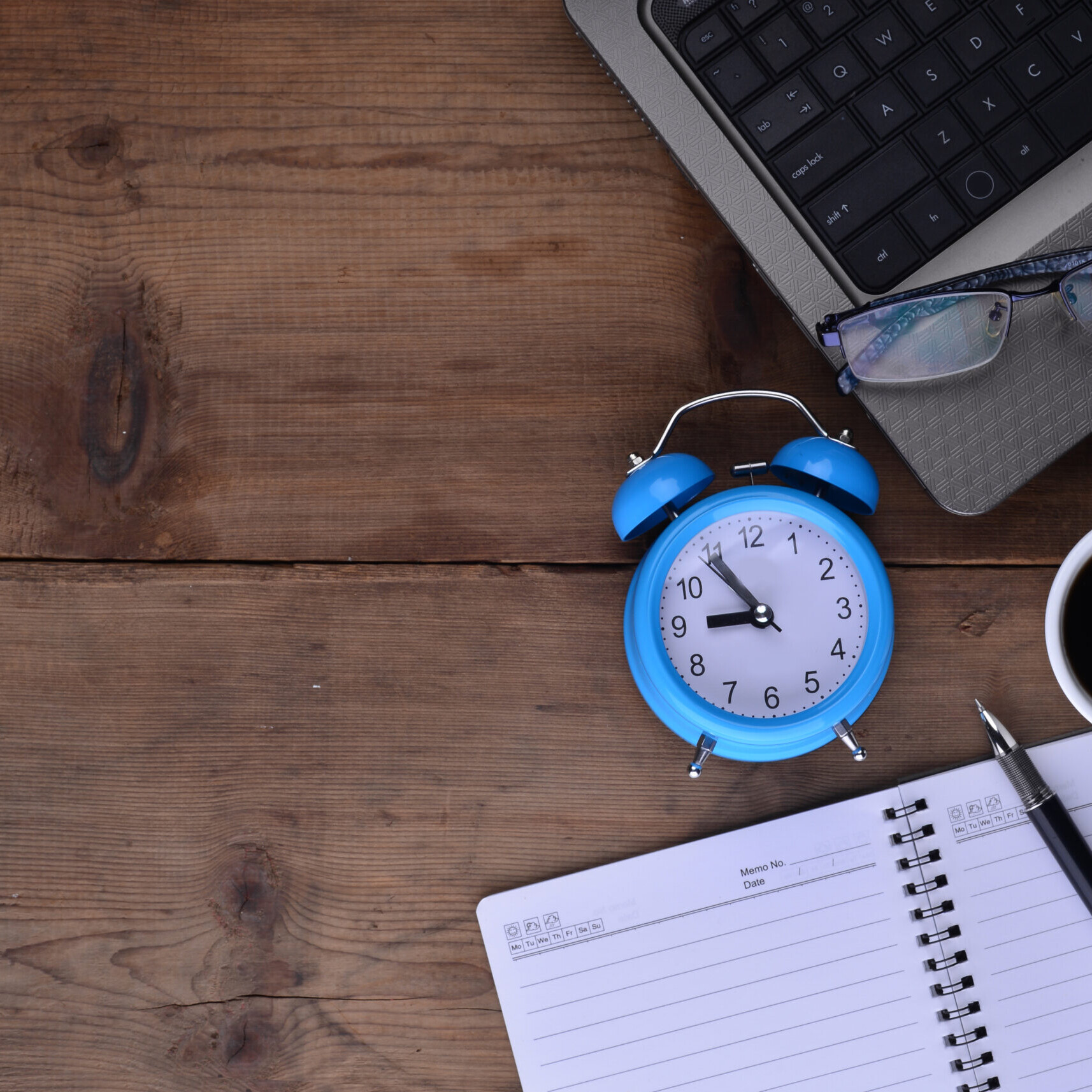 Desk with notebook, clock, laptop, and coffee representing time off policy planning and PTO tracking