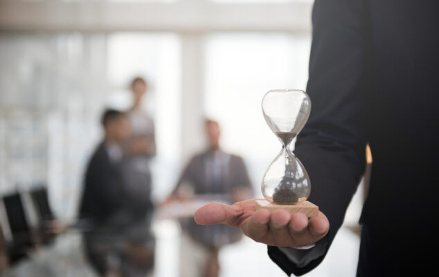 Business professional holding an hourglass symbolizing time management in a workplace discussing a PTO policy template