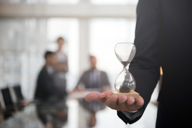 Business professional holding an hourglass symbolizing time management in a workplace discussing a PTO policy template