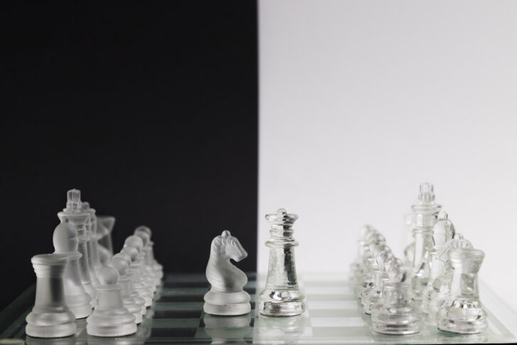Transparent chess pieces facing off on a board, symbolizing Gusto vs ADP comparison