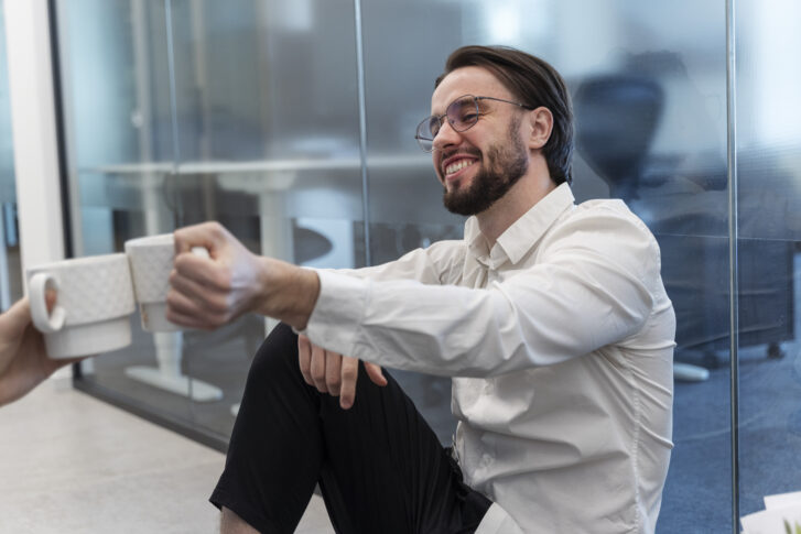 Employee onboarding moment with new hire enjoying coffee in a modern office environment