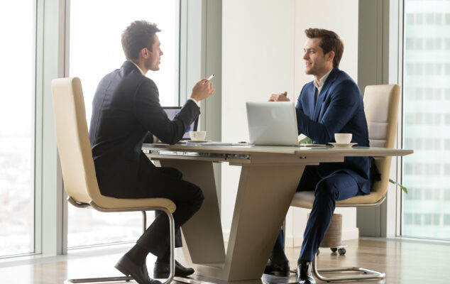 One-on-one meeting questions: two managers talking at a desk